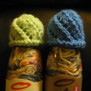 A green spiral-lace hat and a blue one, both on smoothie bottles