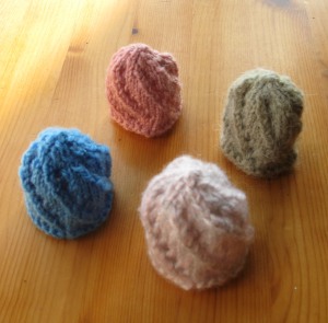 Four spiral hats. One blue, one greenish, one light pink and one dark pink.