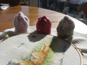 Three spiral hats in front of a view from my window, and behind a half-finished cross stitch.